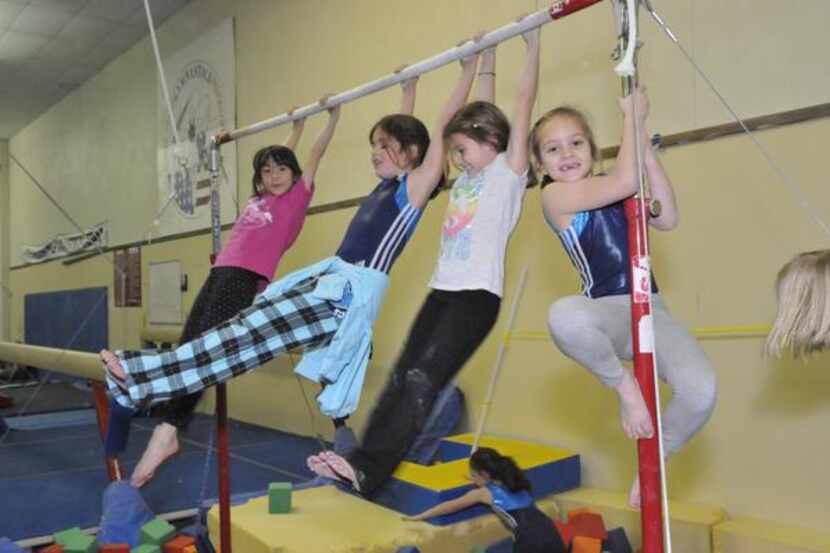 
Children swing on a bar during a class at the Richardson Gymnastics Center. The center...