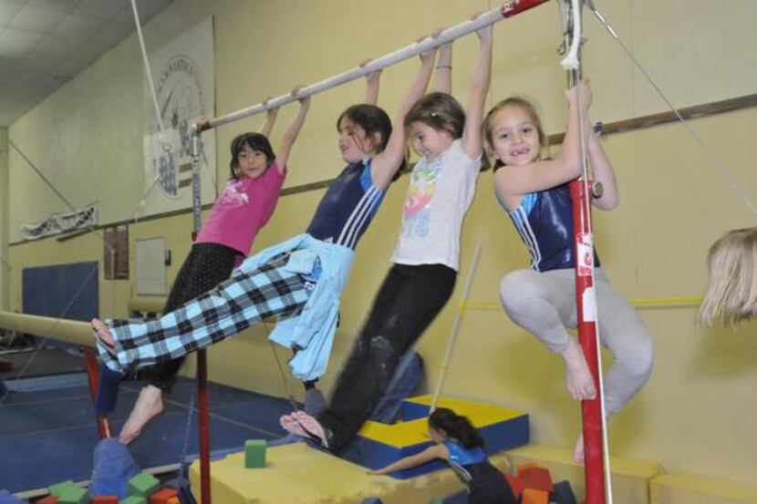 
Children swing on a bar during a class at the Richardson Gymnastics Center. The center...