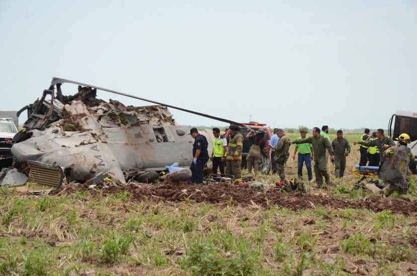 Emergency personnel work next to a navy Blackhawk helicopter crashed after supporting those...