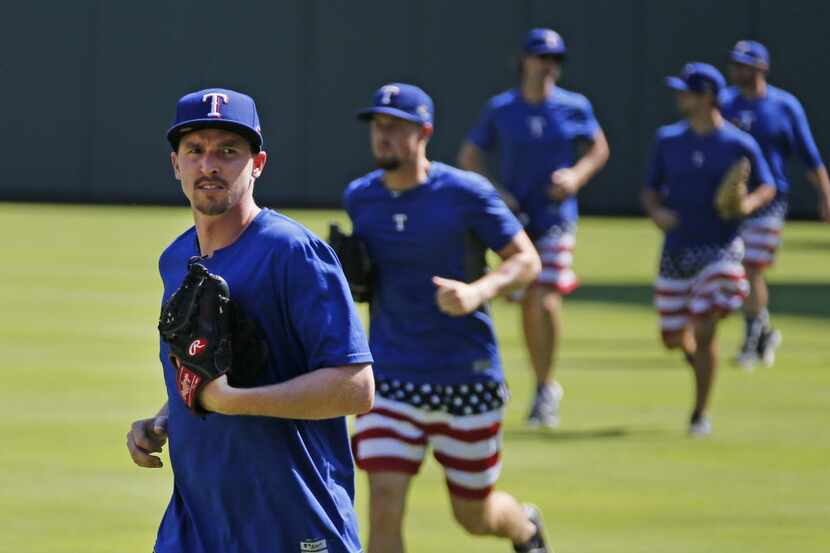 Texas pitcher Tanner Scheppers, left, and other pitchers jog in from the outfield at the end...
