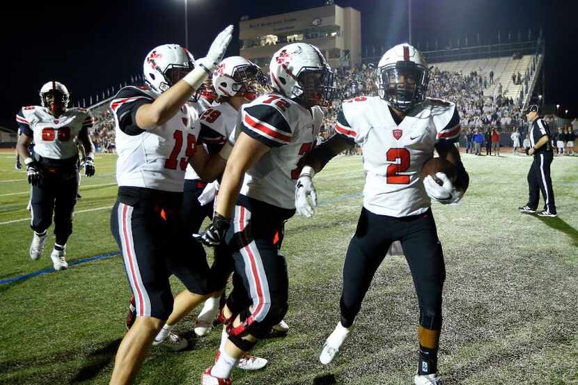 Flower Mound Marcus running back Justin Dinka (2) is congratulated by Jacob Nyboer (72),...