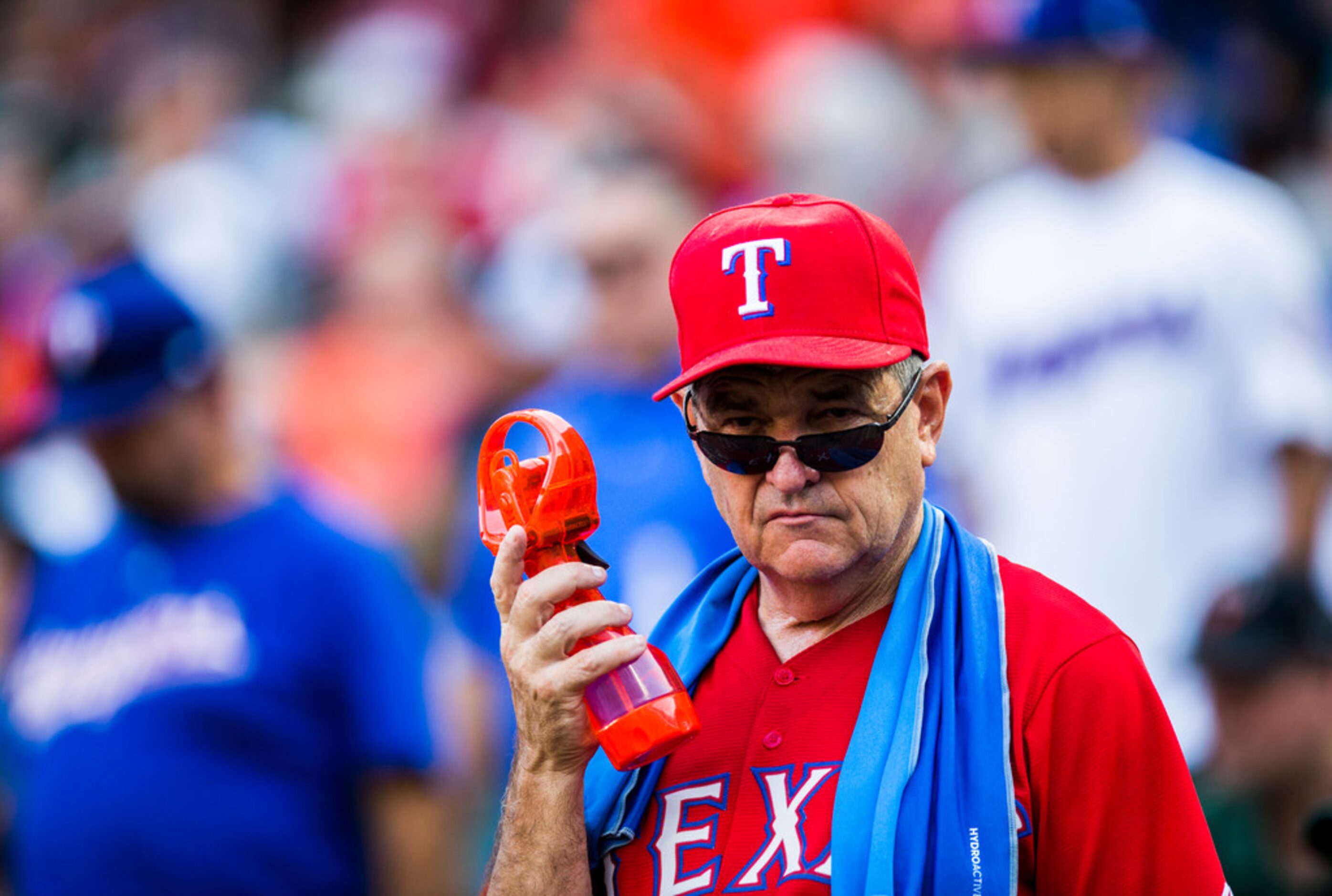 A Rangers fan sprays himself with a portable fan before an MLB game between the Texas...