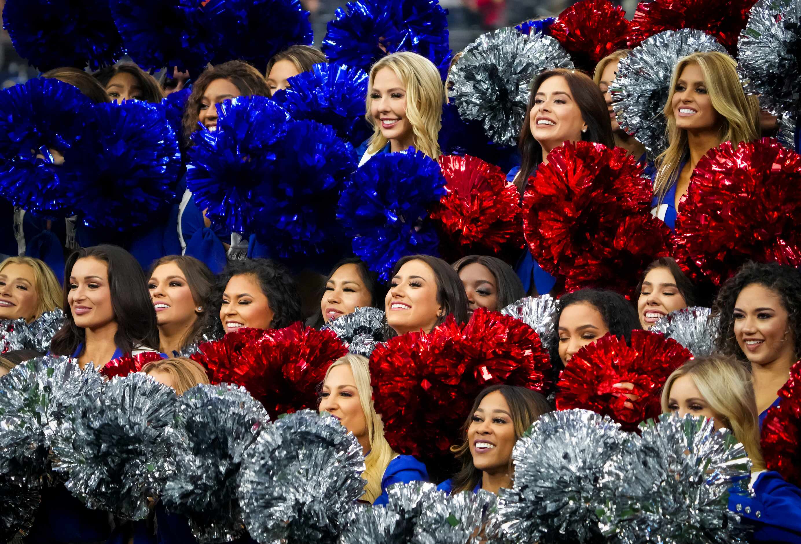 Dallas Cowboys cheerleaders carry silver, white and blue pom poms during halftime of an NFL...