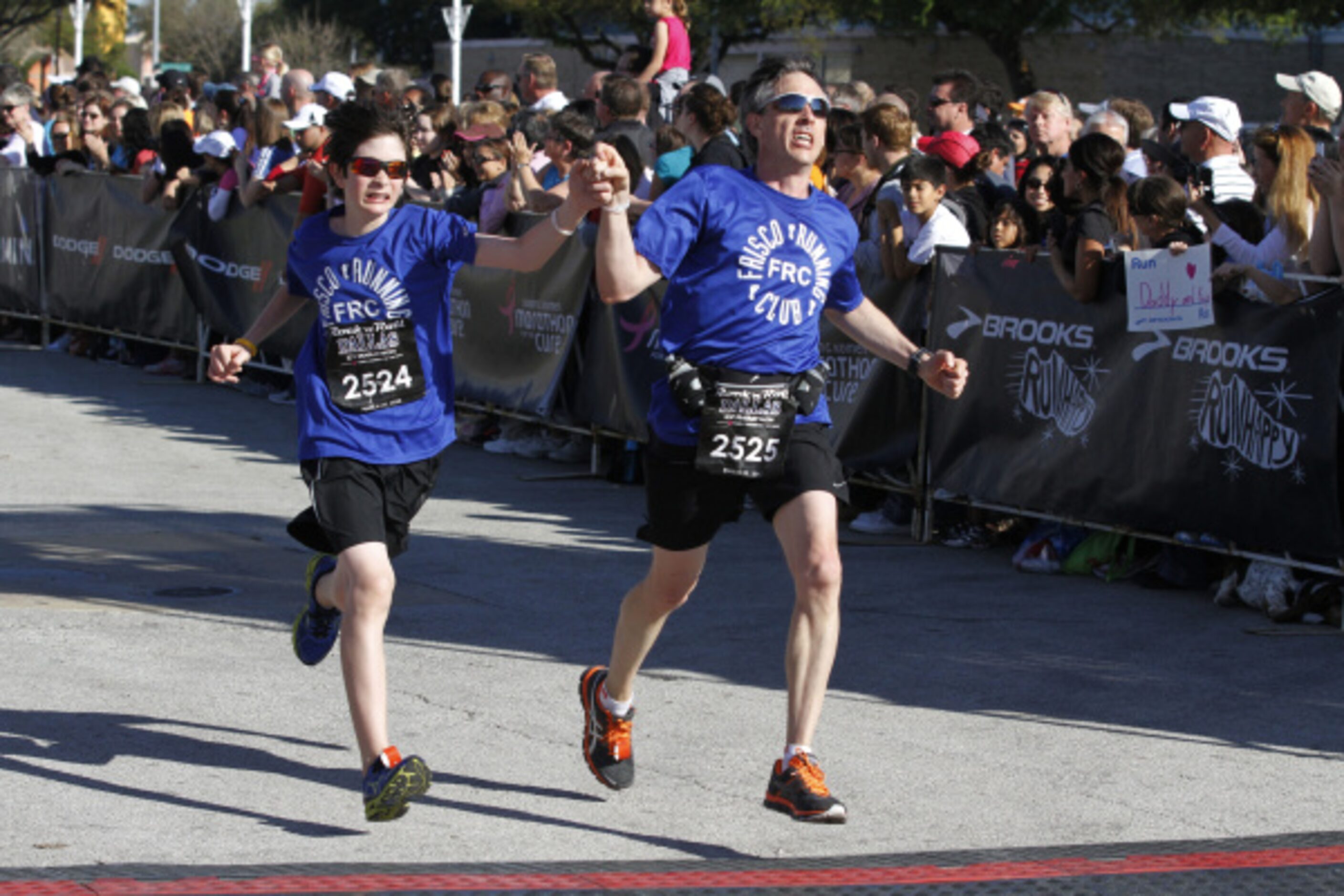 Luke and Dean Malone of Frisco, cross the finish line holding hands during Dallas Rock 'N'...