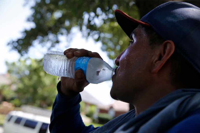 Alejandro Cervantes drinks water on a break as roofer put shingles on a house in Arlington,...