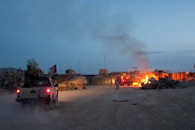 An Afghan National Army pickup truck passes parked U.S. armored military vehicles, as smoke...