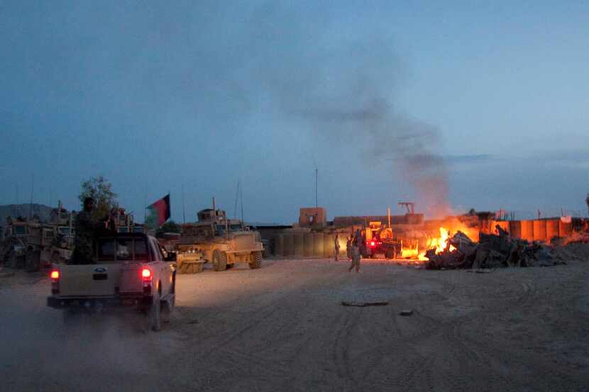 An Afghan National Army pickup truck passed parked U.S. armored military vehicles, as smoke...