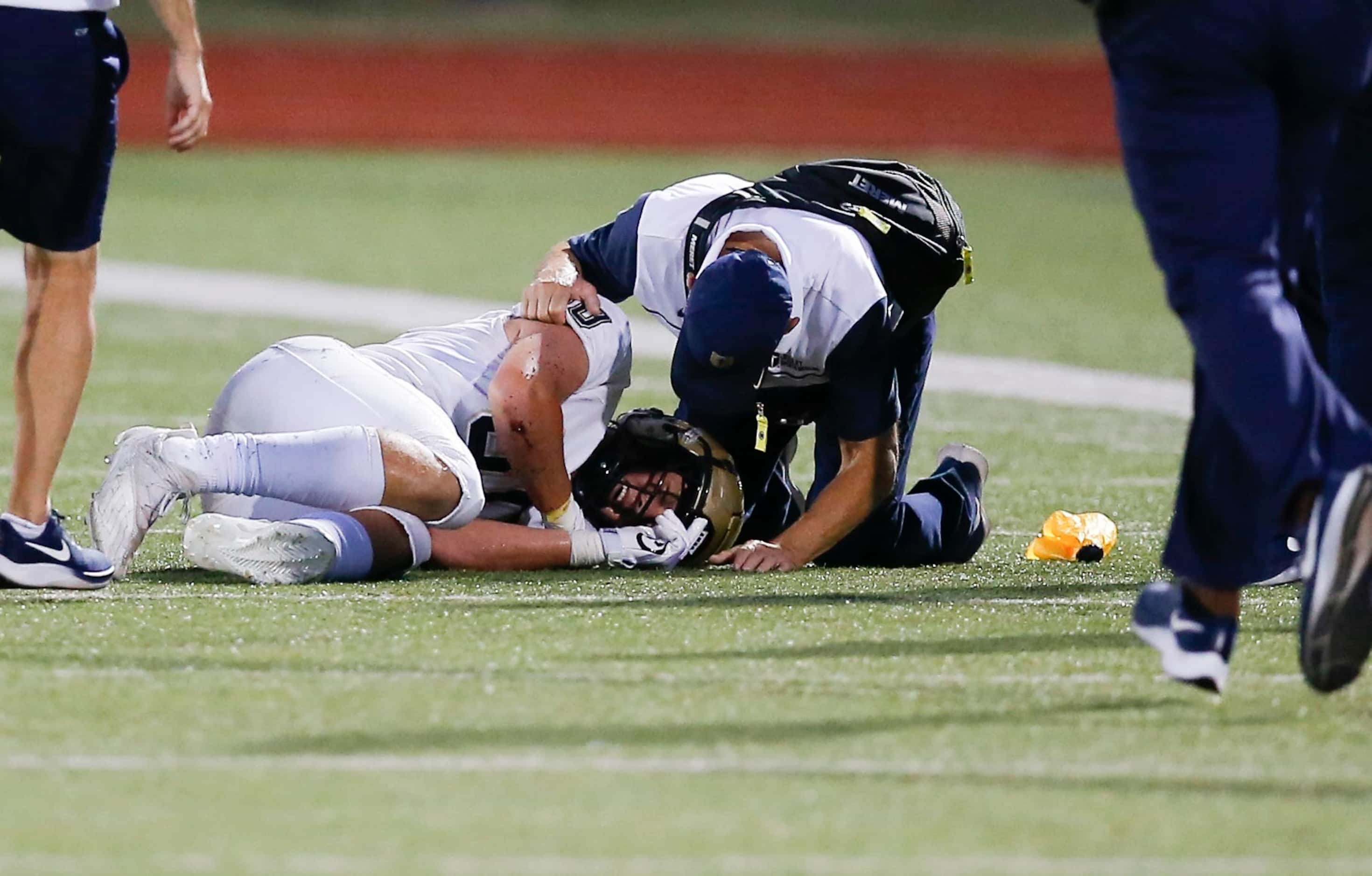 A Jesuit trainer tends to junior wide receiver Matty Wagner (80) after taking a hit from...