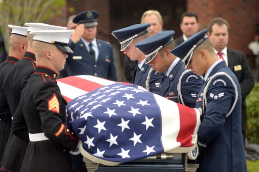 Pall bearers from the Air Force and the Marine Corps move the casket carrying Col. George...