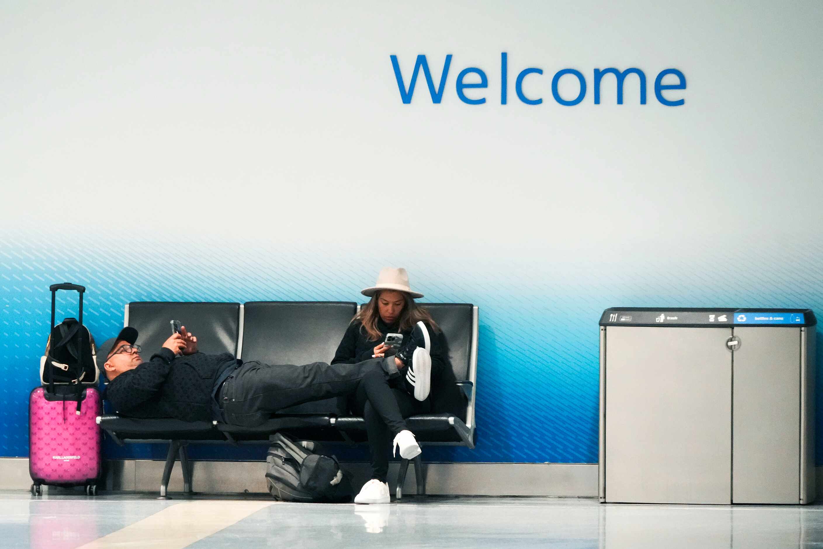 Passengers stretch out near a closed American Airlines ticket counter at DFW International...