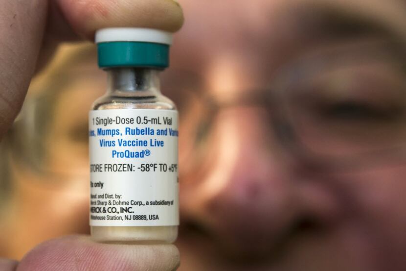 A pediatrician holds a dose of the measles-mumps-rubella (MMR) vaccine at his practice in...