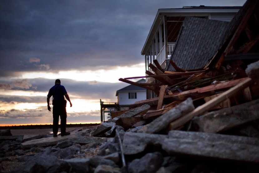 A police officer steps over the remnants of a home leveled by Hurricane Matthew after it hit...