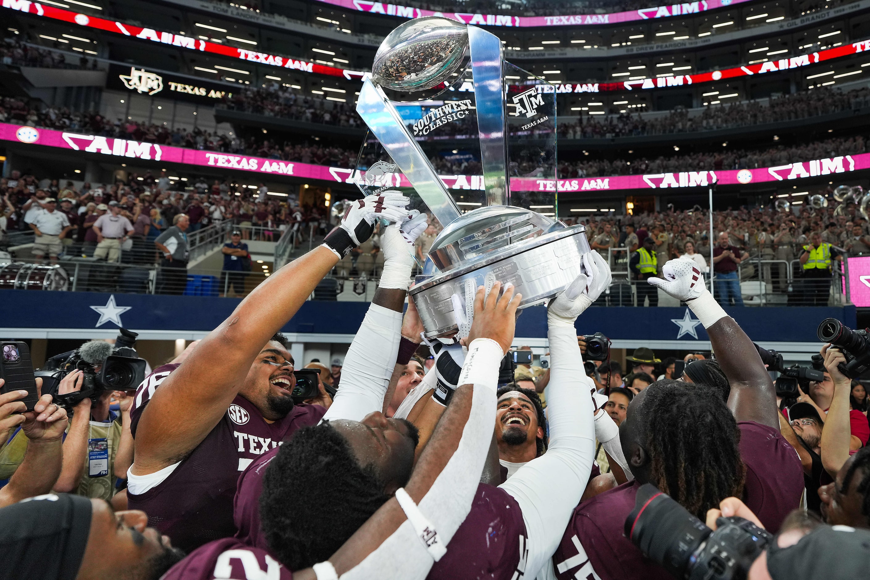 Texas A&M linebacker Taurean York (facing) lifts the Southwest Classic trophy with offensive...