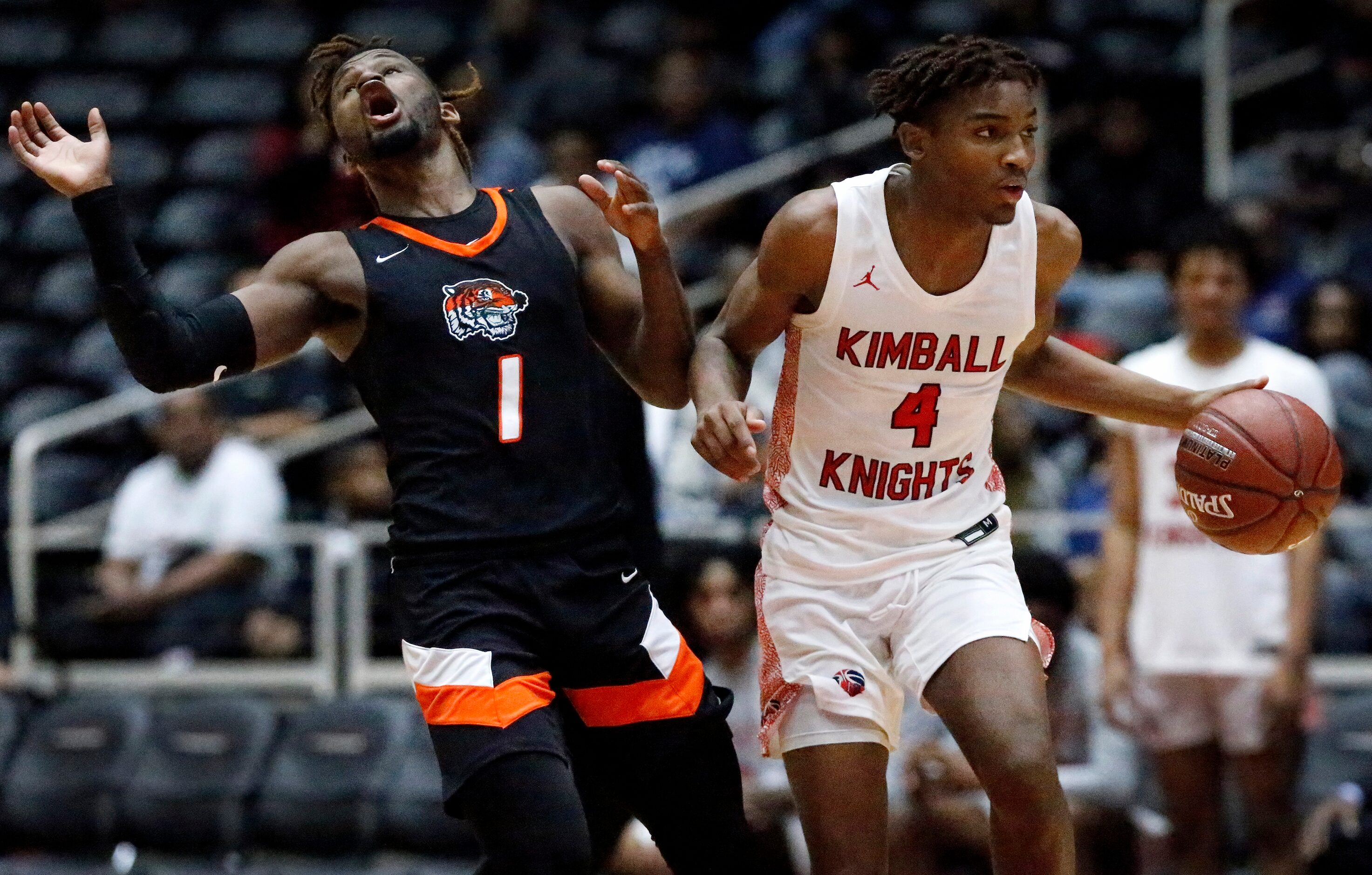 Lancaster High School guard Mike Miles (1) tries to draw a charge foul on Kimball High...