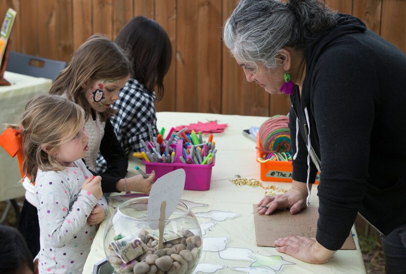 Ofelia Faz-Garza helps Ruby Shearer, 5, create a holiday ornament at a holiday bazaar at the...