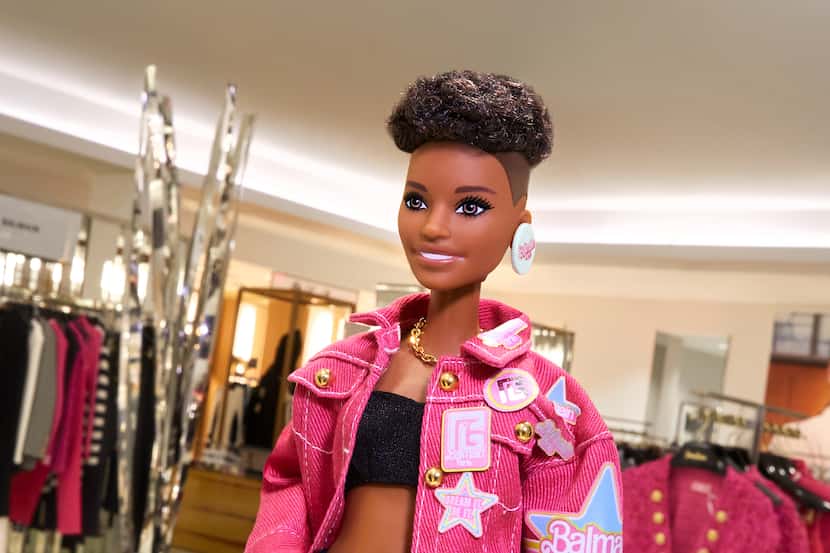 Barbie mannequin wearing an oversize denim jacket with embroidered badges that's part of the...