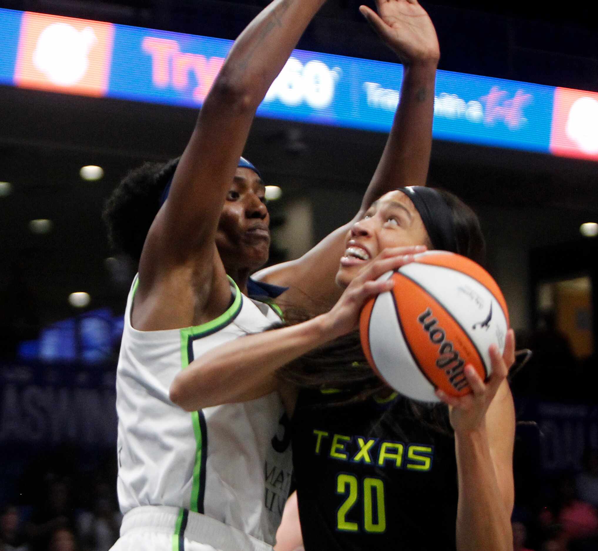 Dallas Wings forward Isabelle Harrison (20) eyes a shot against the defense of Minnesota...