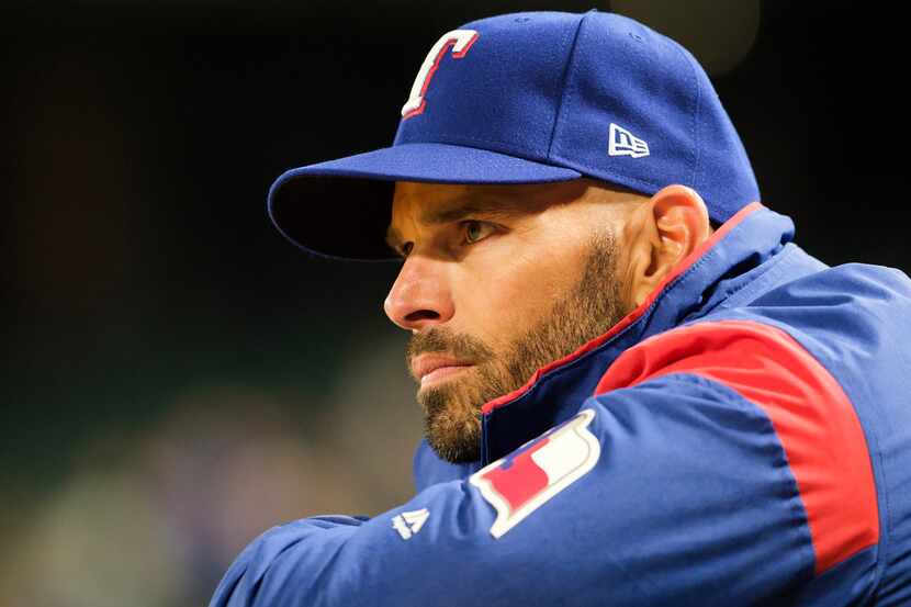 Texas Rangers manager Chris Woodward watches from the dugout during the seventh inning...