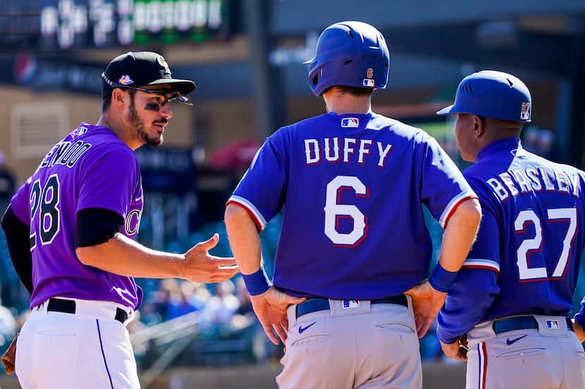Rockies third baseman Nolan Arenado chats with Rangers infielder Matt Duffy (6) and third...