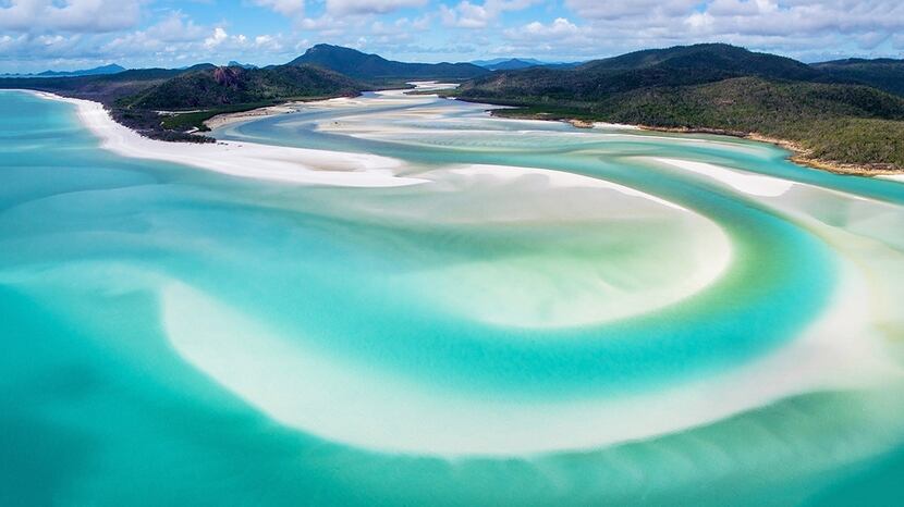 Surreal blue pastels are drawn by the powder-white sands of Whitehaven Beach as it meets...