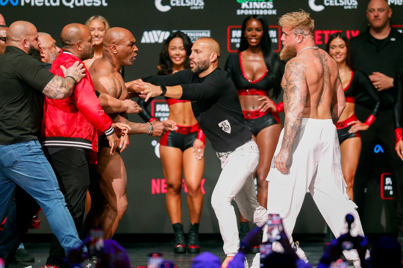 Mike Tyson is held back by his team after slapping Jake Paul as they faced-off during public...