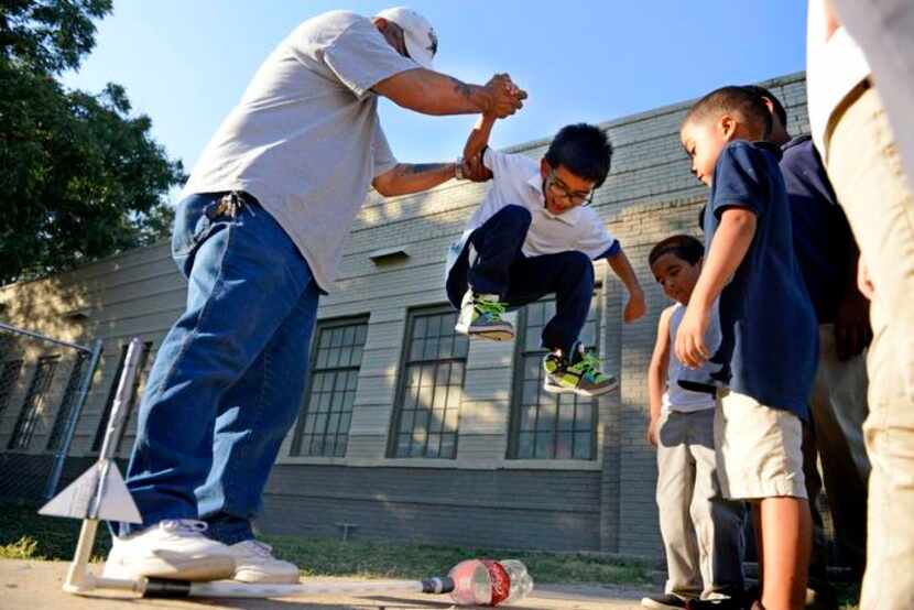 
Employee John Sanchez helps Jaiden Martinez, 6, jump on a Coca-Cola bottle to release a...