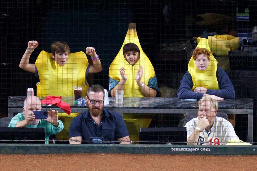 Three young fans wearing banana suits cheer during the first inning in Game 2 of the World...