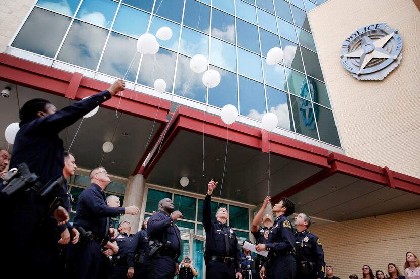 Dallas police officers released balloons Friday during a ceremony for the officers slain in...