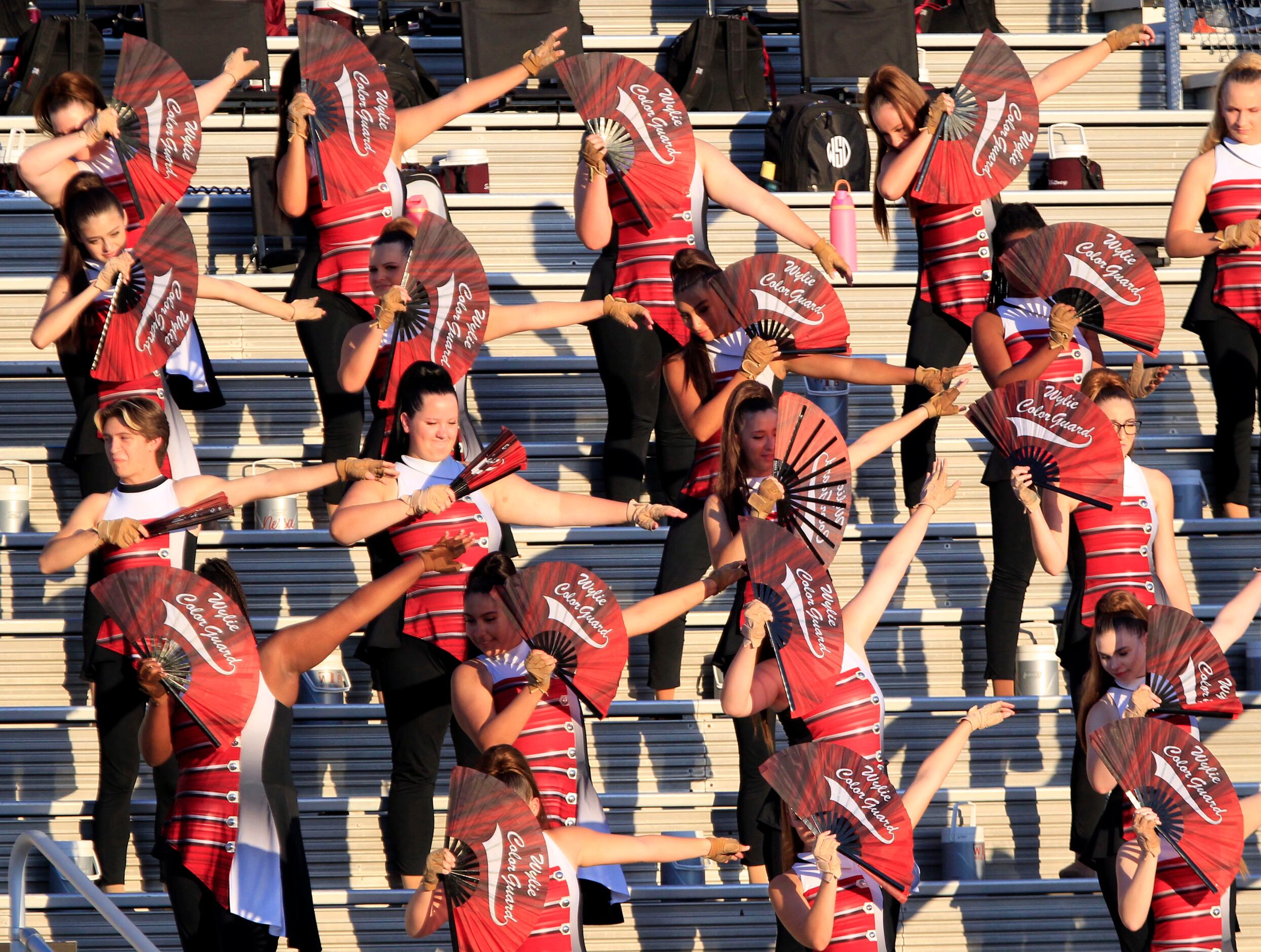 The Wylie High Color Guard sports hand fans, as they sit in the sunlight, before the start...