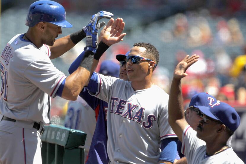 Texas Rangers' Alex Rios, left, gets congratulations from the bench after hitting a solo...