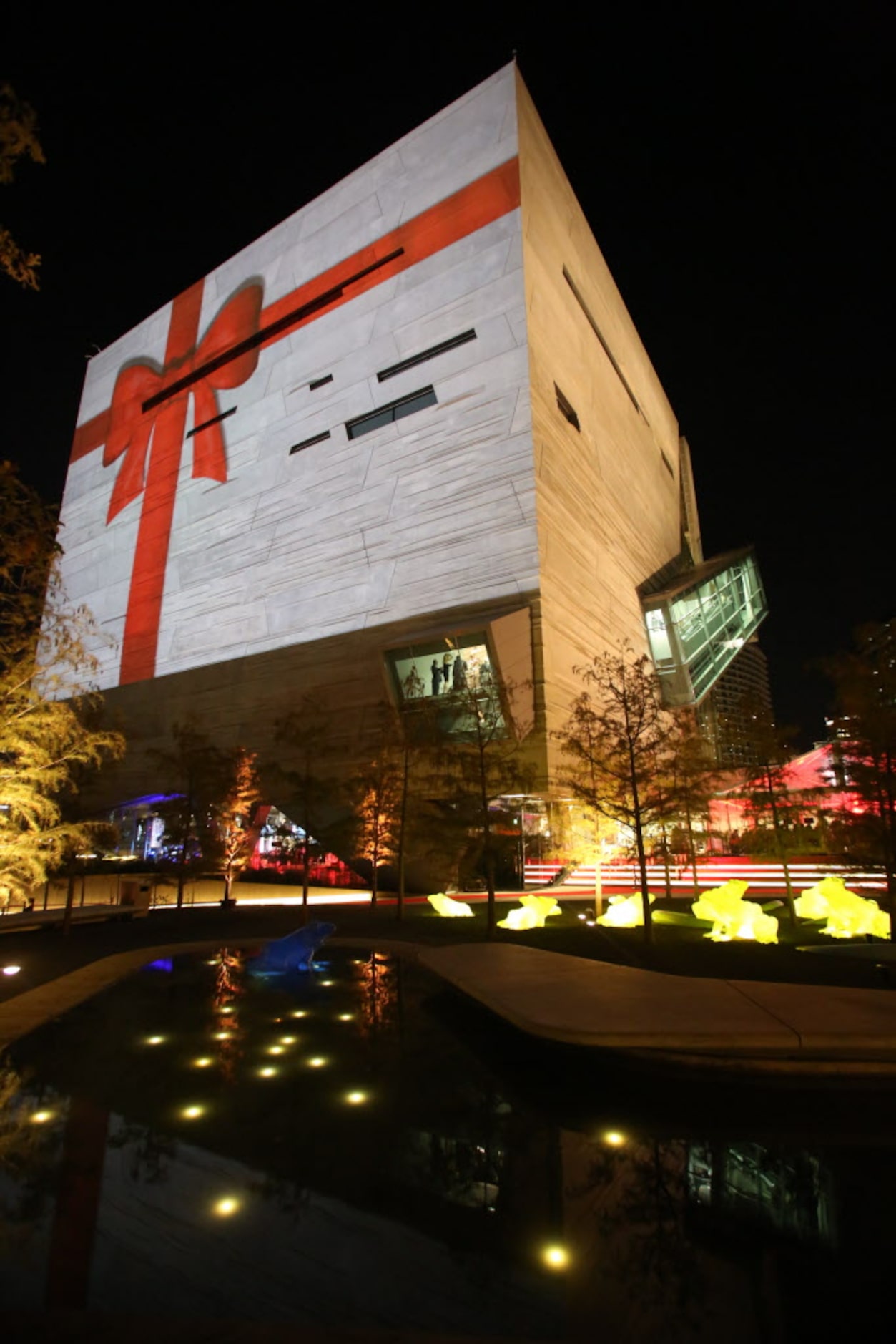 An image of a giant red bow is projected on the outside wall of the Perot Museum of Nature...