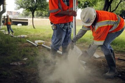  Workers pour concrete as they fence in a closing section of Tent City Tuesday, April 26,...