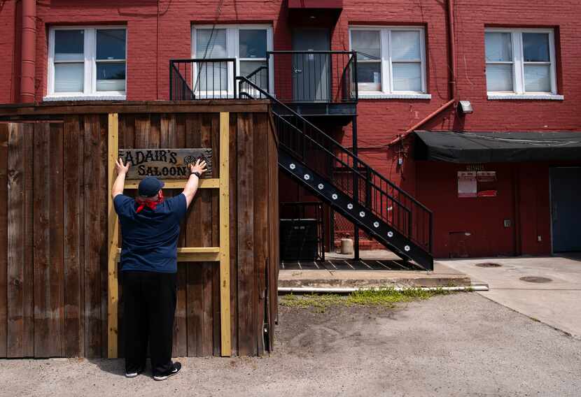 Owner Joel Morales of Adair's Saloon hangs signage as he prepares his outdoor patio for...