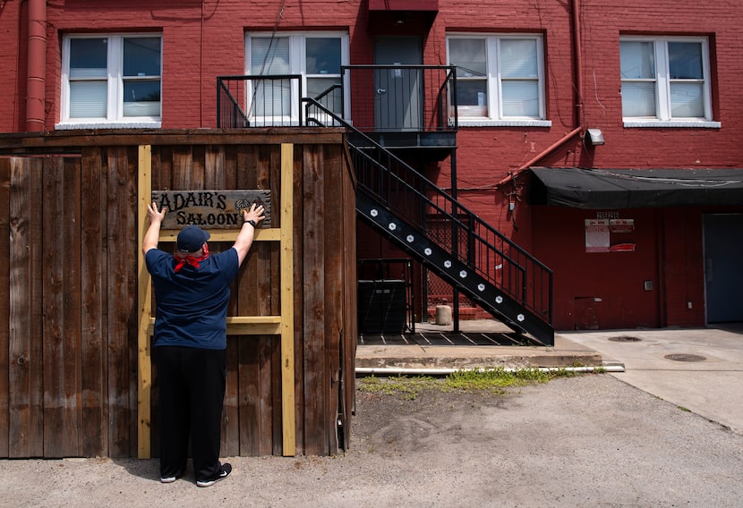 Owner Joel Morales of Adair's Saloon hangs signage as he prepares his outdoor patio for...