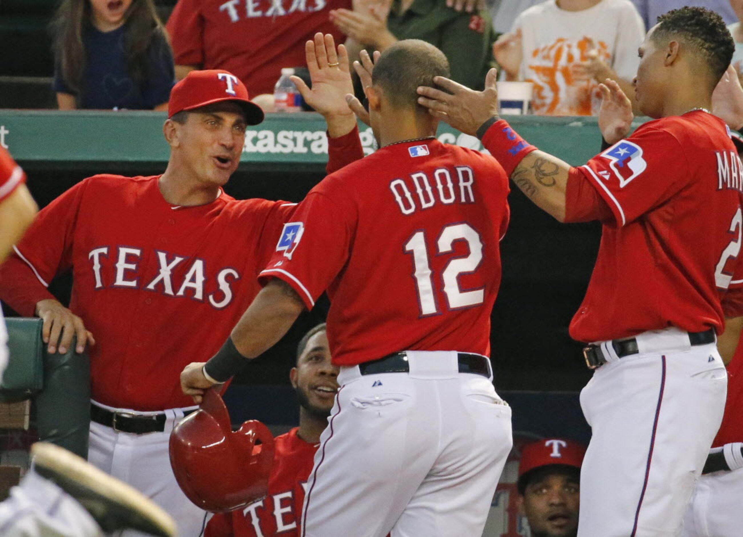 Texas manager Tim Bogar greets Rougned Odor after Odor scored a run in the first inning...