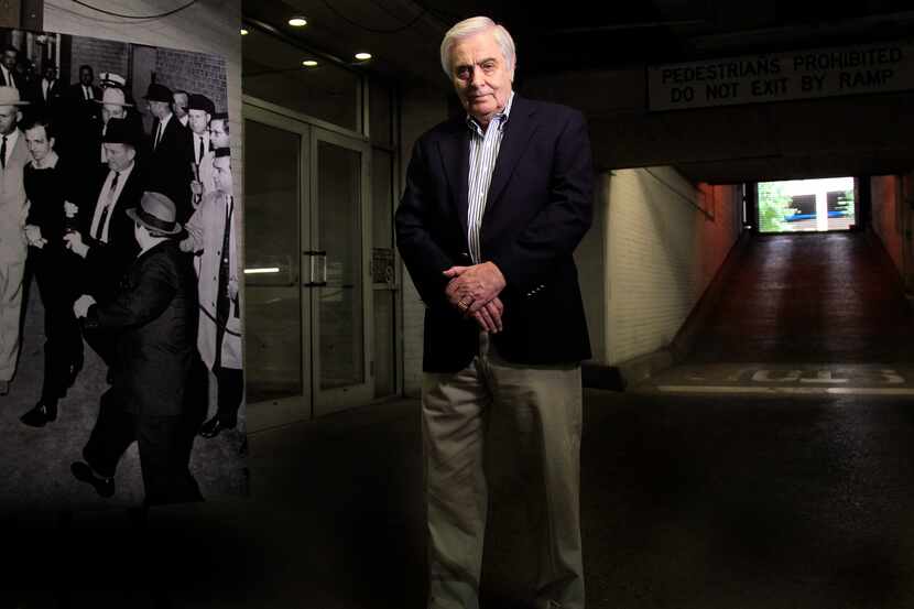 Hugh Aynesworth poses in 2013 beside a photograph of Jack Ruby shooting and killing Lee...