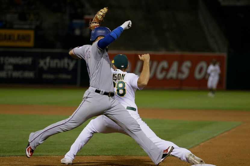 Texas Rangers' Robinson Chirinos runs to first base as Oakland Athletics first baseman Matt...