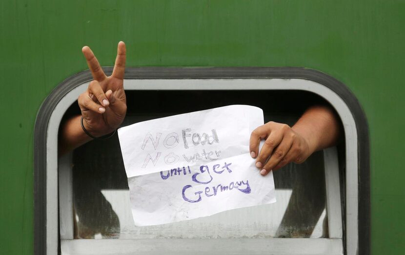 A man displays  a sign out the window of a train that was stopped Friday in Bicske, Hungary.