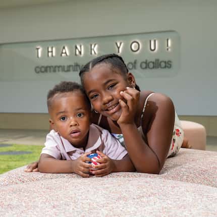 A portrait of two Black children in front of a sign that reads "Thank you! Community...