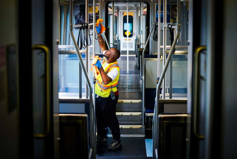 Kenneth Evans wiped down hand rails with disinfectant as he cleaned a DART rail train at the...