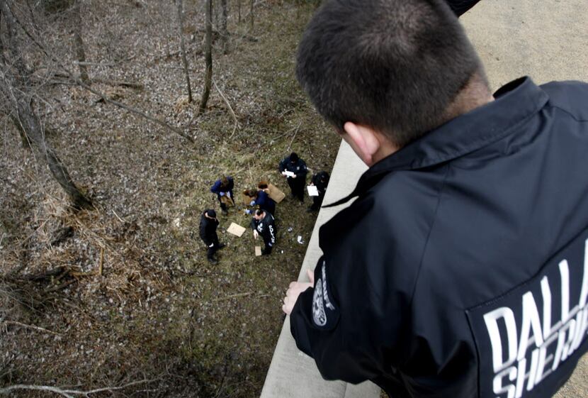 Dallas County Deputy Michael Ortiz watches a forensic team collect evidence in an area of...