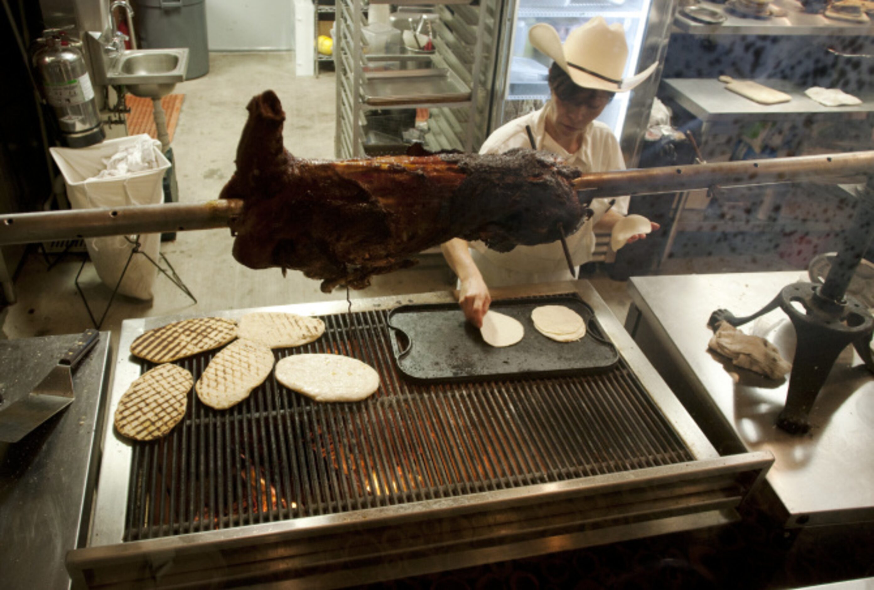 WOODSHED SMOKEHOUSE: A cook makes tortillas in the kitchen.