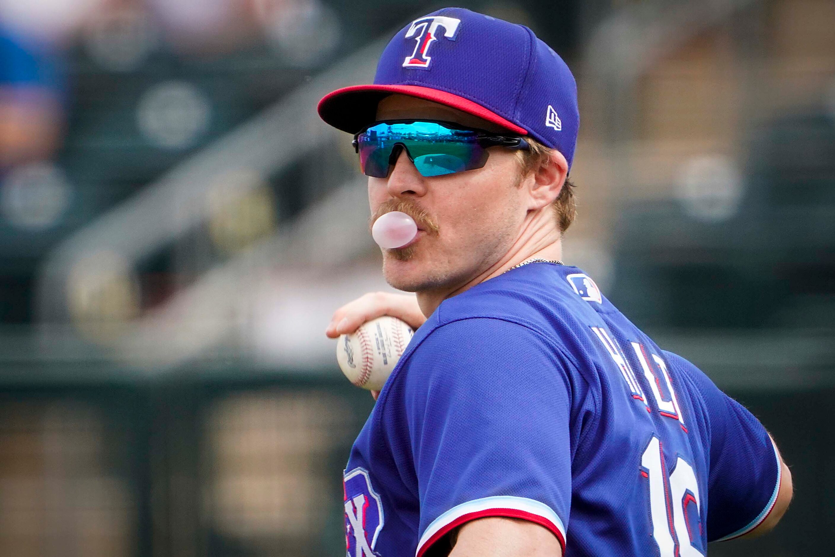 Texas Rangers second baseman Brock Holt blows a bubble as he brings the ball back into the...