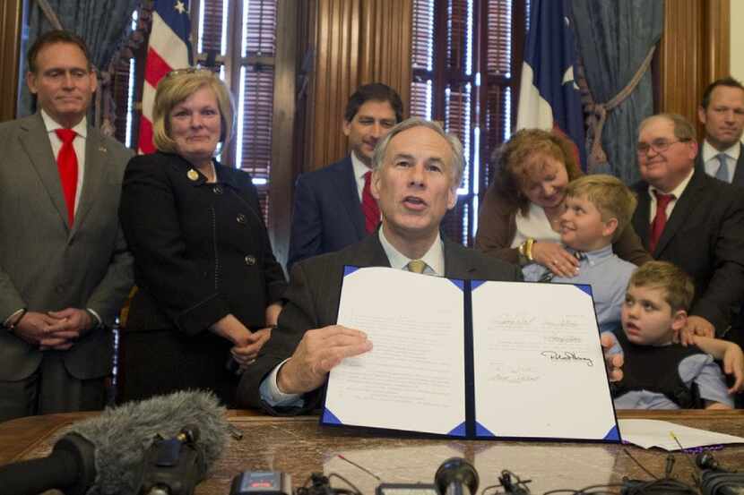 Gov. Greg Abbott displays Senate Bill 339 after signing it into law in 2015. The bill allows...