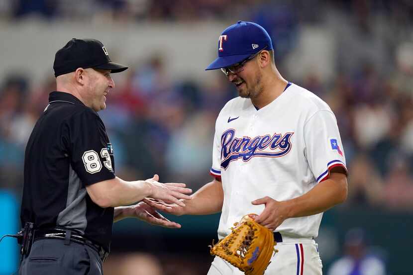 Texas Rangers starting pitcher Dane Dunning, right, has a laugh with umpire Mike Estabrook...