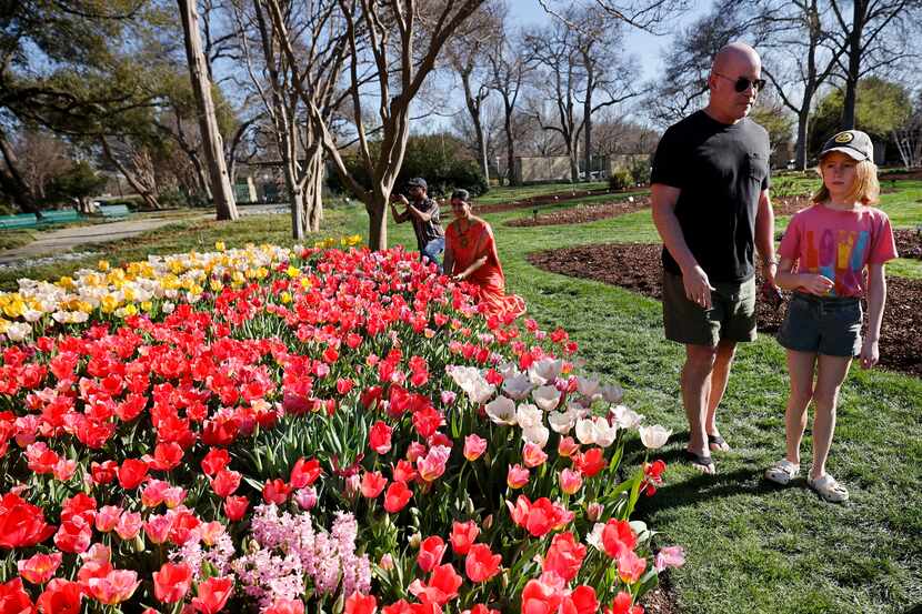 Iden Ritchie, 10 of Dallas and her father Ronnie Ritchie walk by flowers at the Dallas...