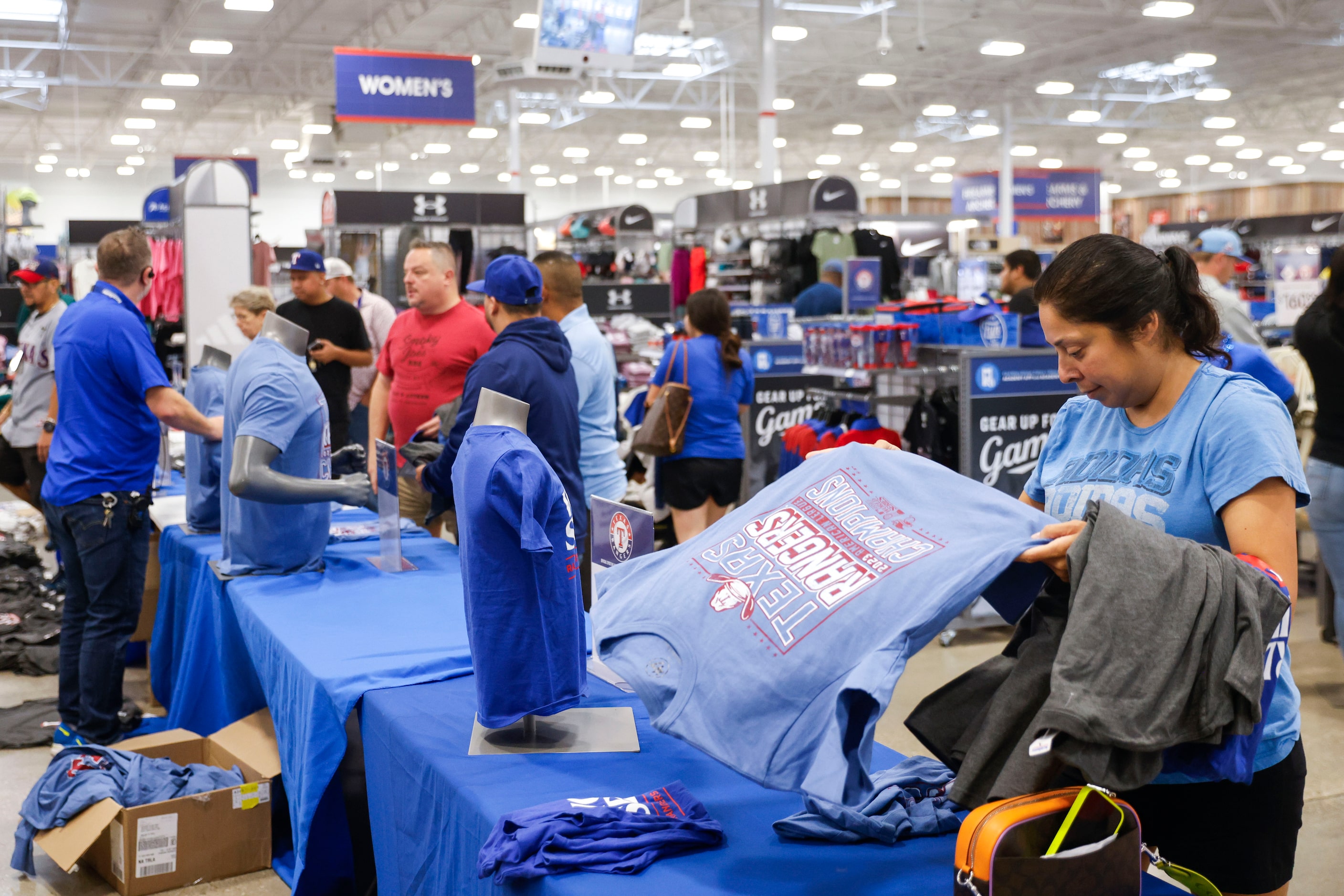 Denise Devora-Gamboa of Dallas flips open a Texas Rangers shirt as she shops around Academy...