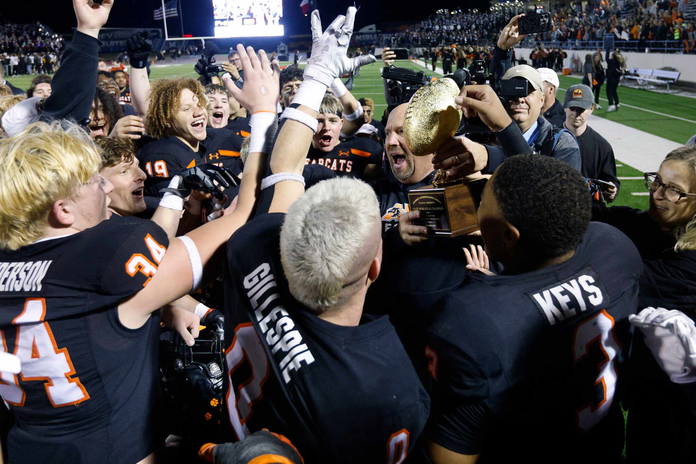 Aledo head coach Robby Jones raises the state semifinal championship trophy after defeating...