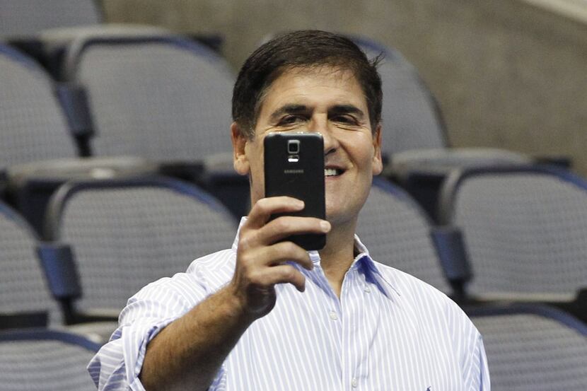 Dallas Mavericks owner Mark Cuban uses his phone prior to the start of a press conference...