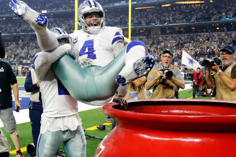 Dallas Cowboys running back Ezekiel Elliott (21) throws quarterback Dak Prescott (4) into...